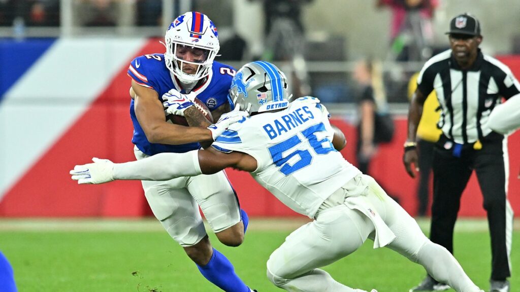 Buffalo Bills wide receiver DJ Moore holds the ball as Detroit Lions linebacker Derrick Barnes wraps him up.