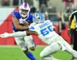 Buffalo Bills wide receiver DJ Moore holds the ball as Detroit Lions linebacker Derrick Barnes wraps him up.