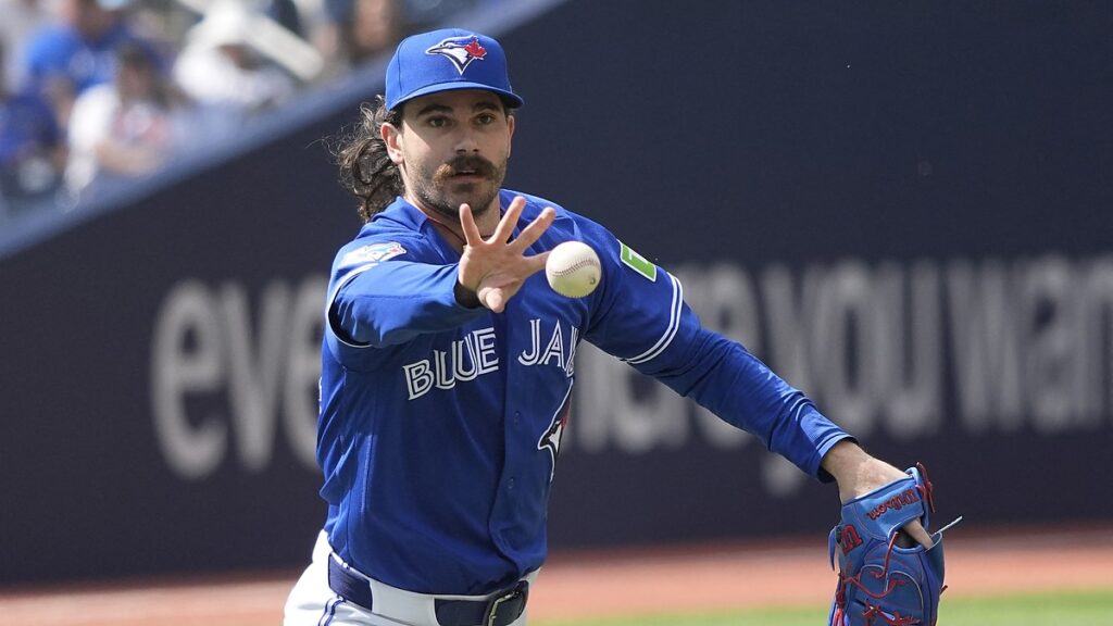 Toronto Blue Jays starting pitcher Dylan Cease flips the ball toward first base after fielding a grounder.