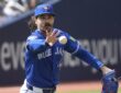 Toronto Blue Jays starting pitcher Dylan Cease flips the ball toward first base after fielding a grounder.