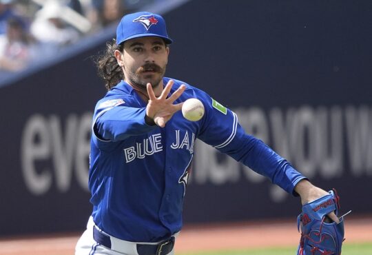 Toronto Blue Jays starting pitcher Dylan Cease flips the ball toward first base after fielding a grounder.