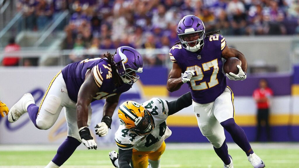 Minnesota Vikings running back Jordan Mason carries the ball past a diving Green Bay Packers linebacker Zaire Franklin.