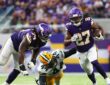 Minnesota Vikings running back Jordan Mason carries the ball past a diving Green Bay Packers linebacker Zaire Franklin.