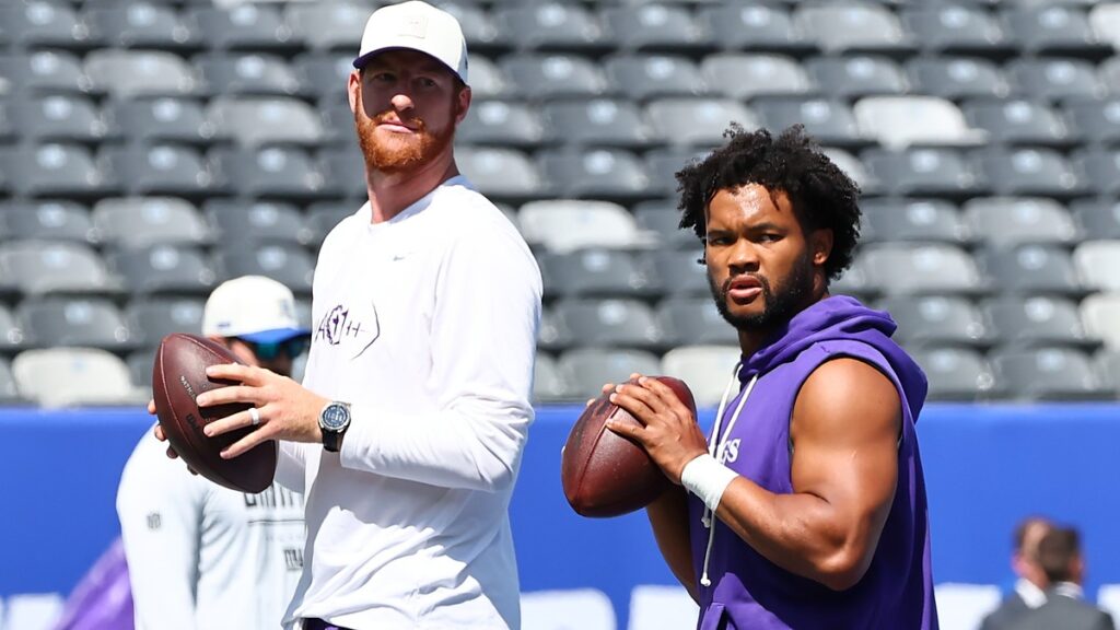 Minnesota Vikings quarterbacks Kyler Murray and Carson Wentz each hold a football as they warm up before a game.