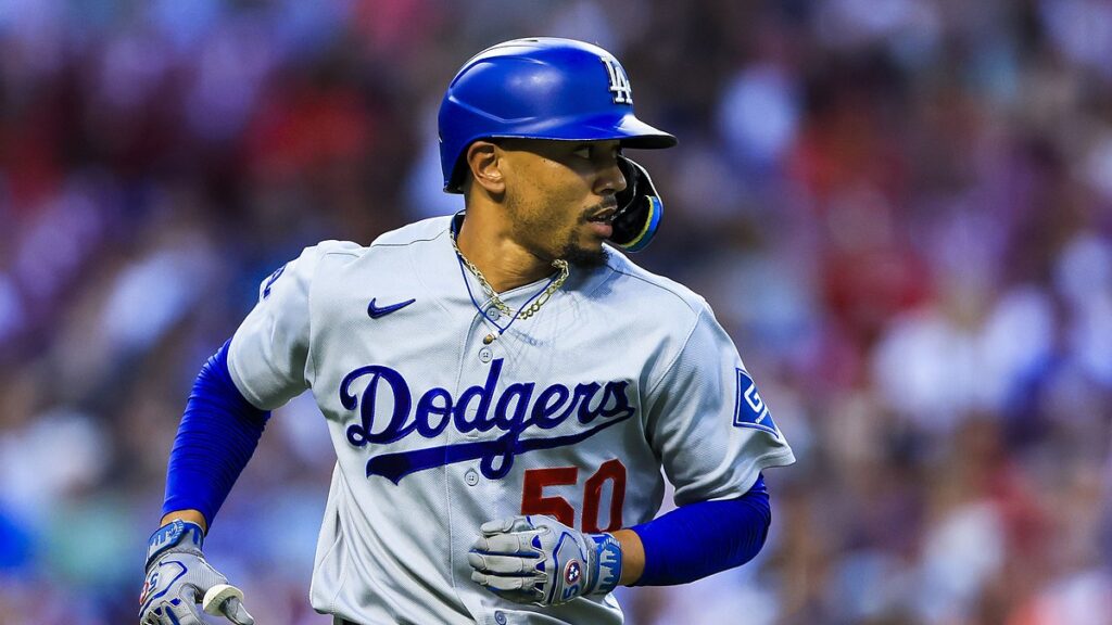 Los Angeles Dodgers shortstop Mookie Betts runs toward first base in his helmet and batting gloves.
